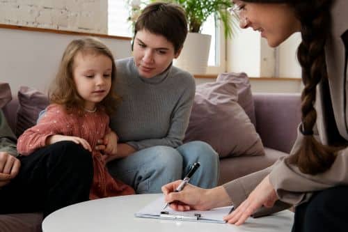 Autistic kid being held by mother as they process insurance papers