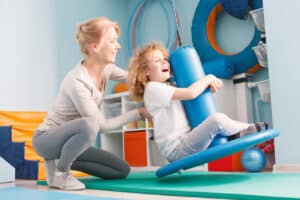 A therapist helps an autistic child develop skills using a sensory swing.