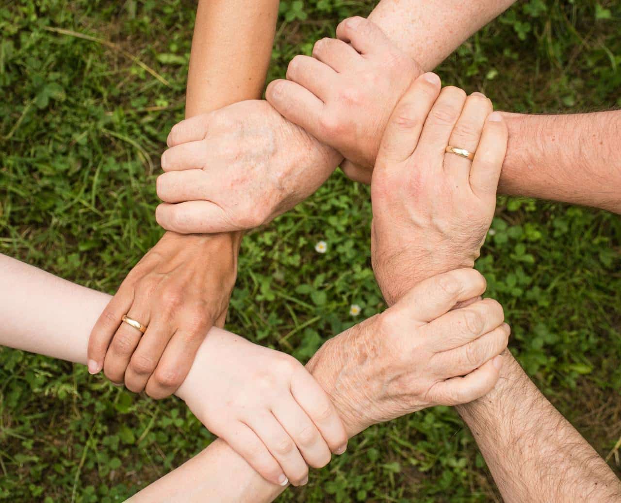 Different hands holding the next person's wrist to form a circle