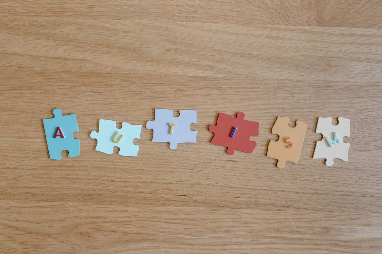 autism spelled out in puzzle pieces on wooden floor