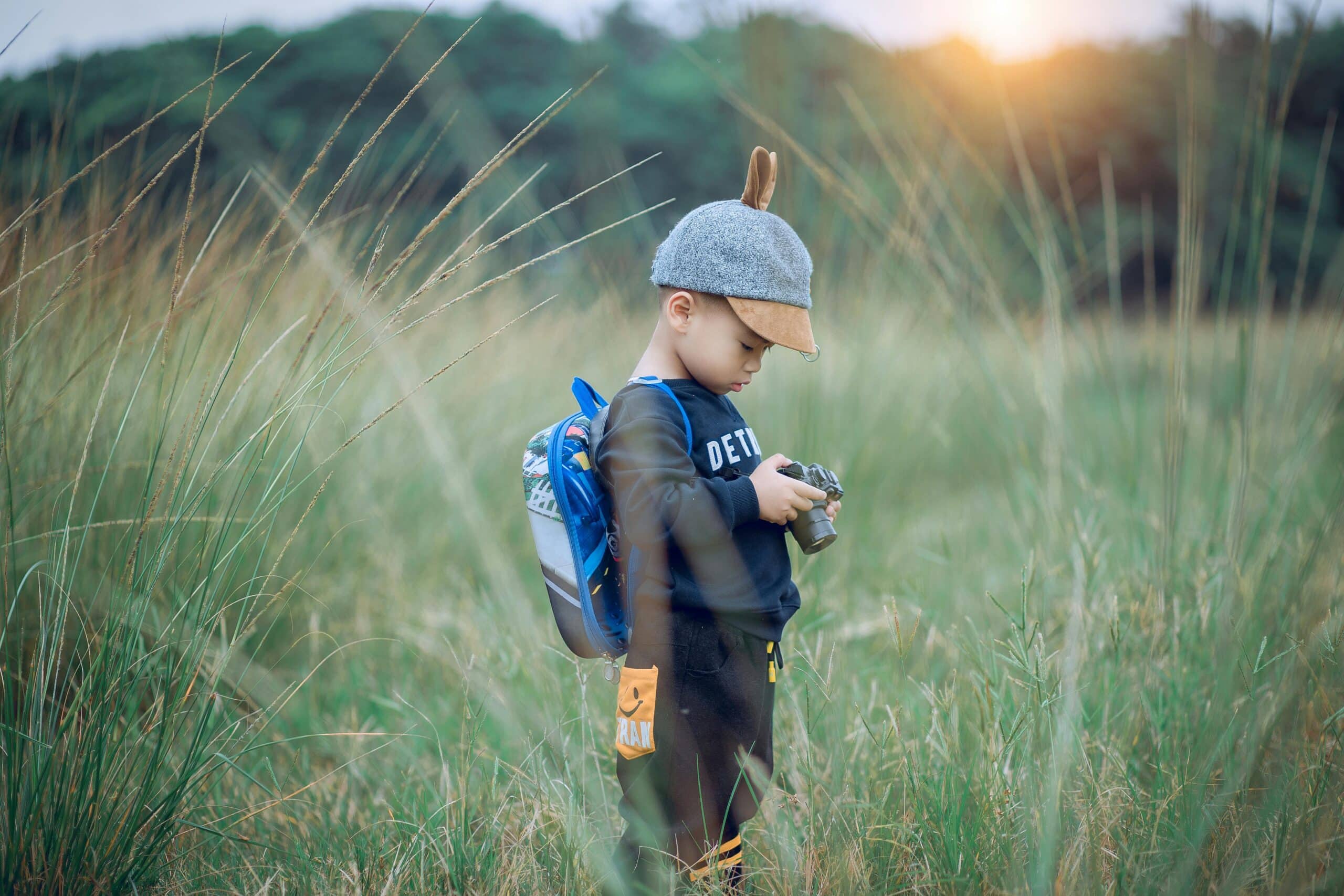 child holding a camera in the middle of a field