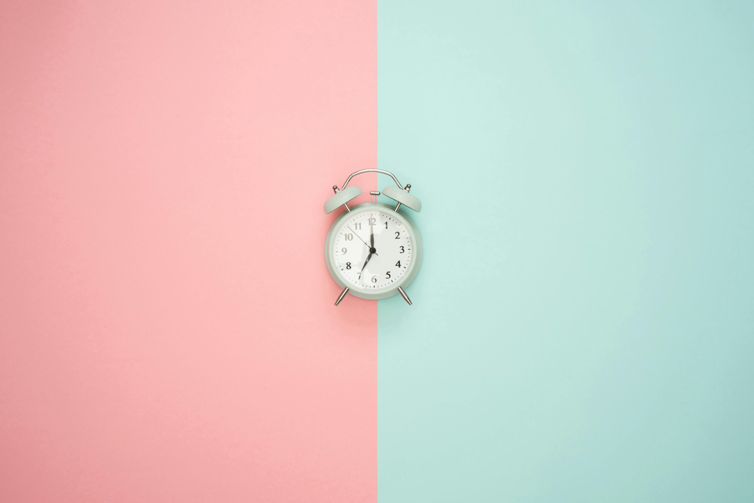 clock placed in between pastel pink and pastel green wall