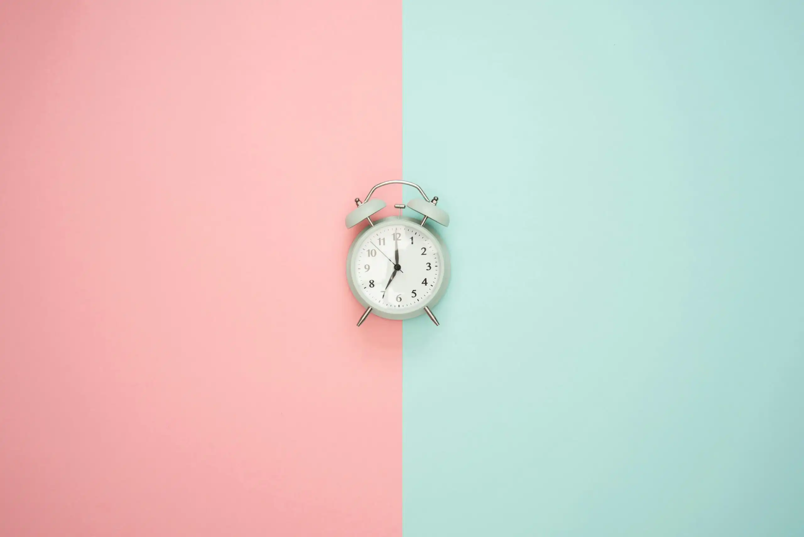 clock placed in between pastel pink and pastel green wall