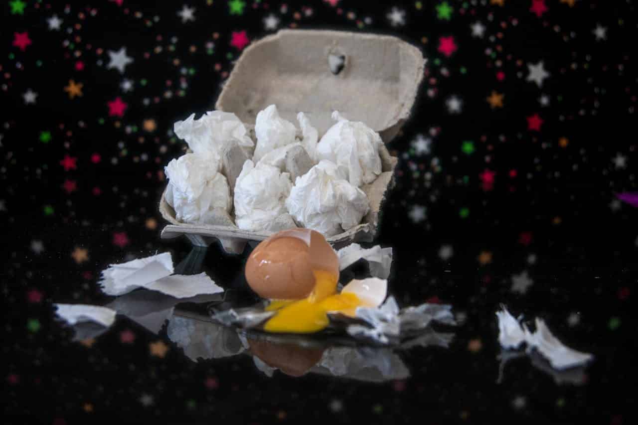 falling carton of eggs filled with crumpled mozarella balls and a falling broken egg