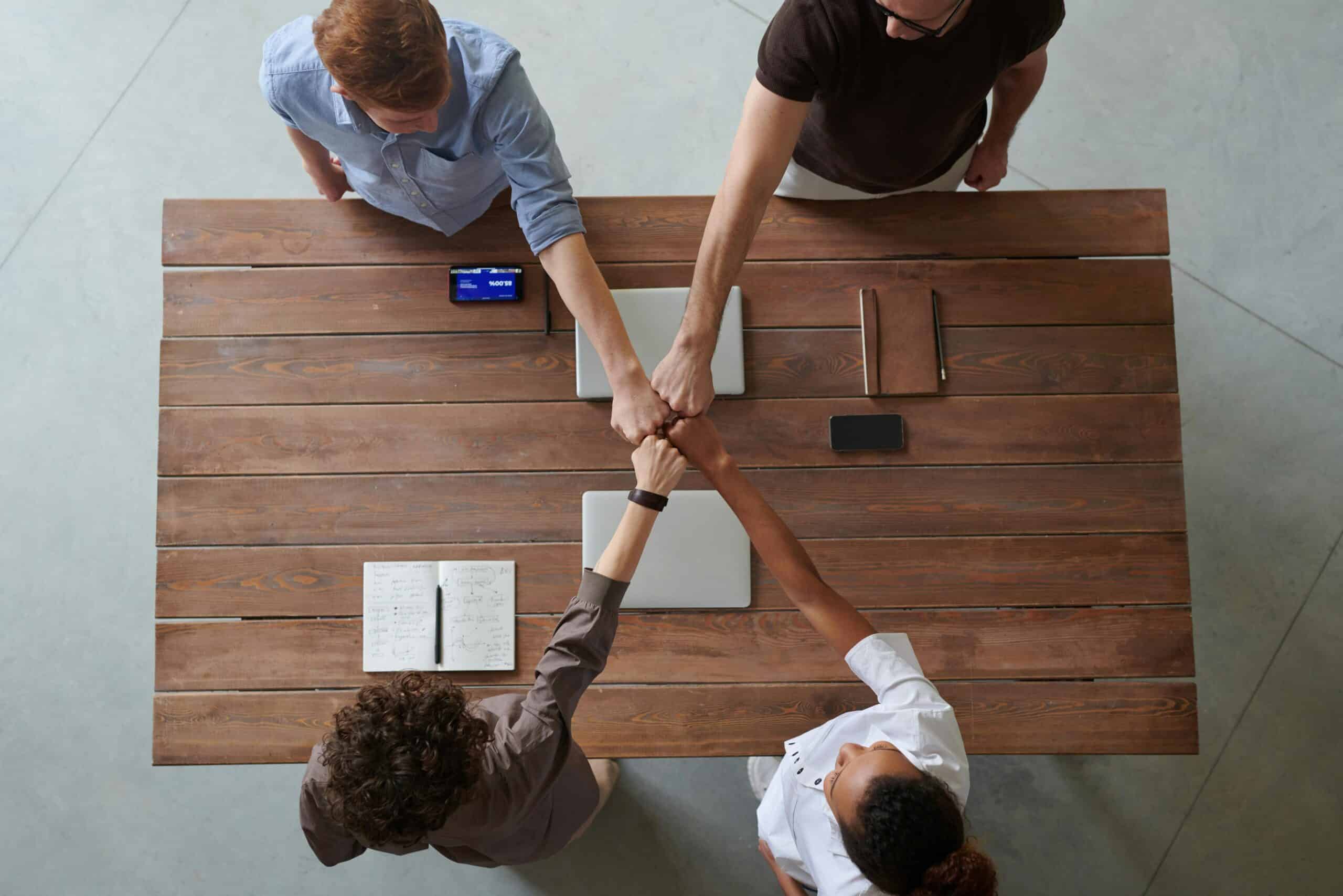 four person fist bumb above the desk