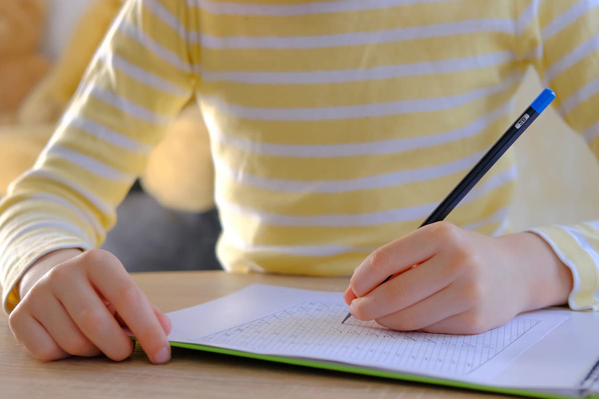 A close-up of a red alarm clock, pencil, eraser, and sharpened pencil on top of filled-in scantron sheets, symbolizing the preparation for the BCBA exam