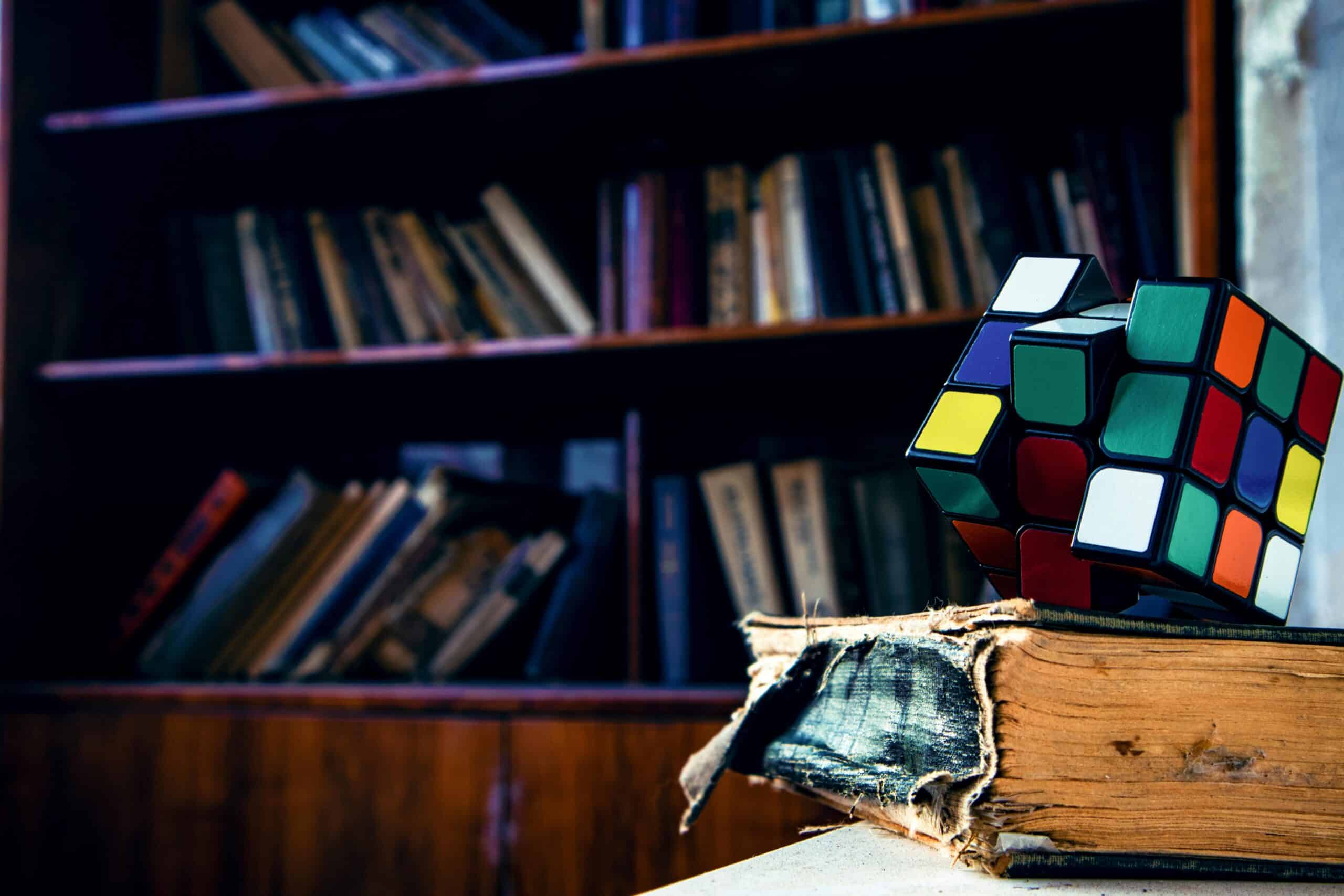 unsolve rubix cube on top of a worn book