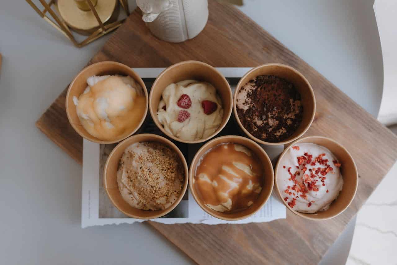 different ice cream flavors in cups with spoons