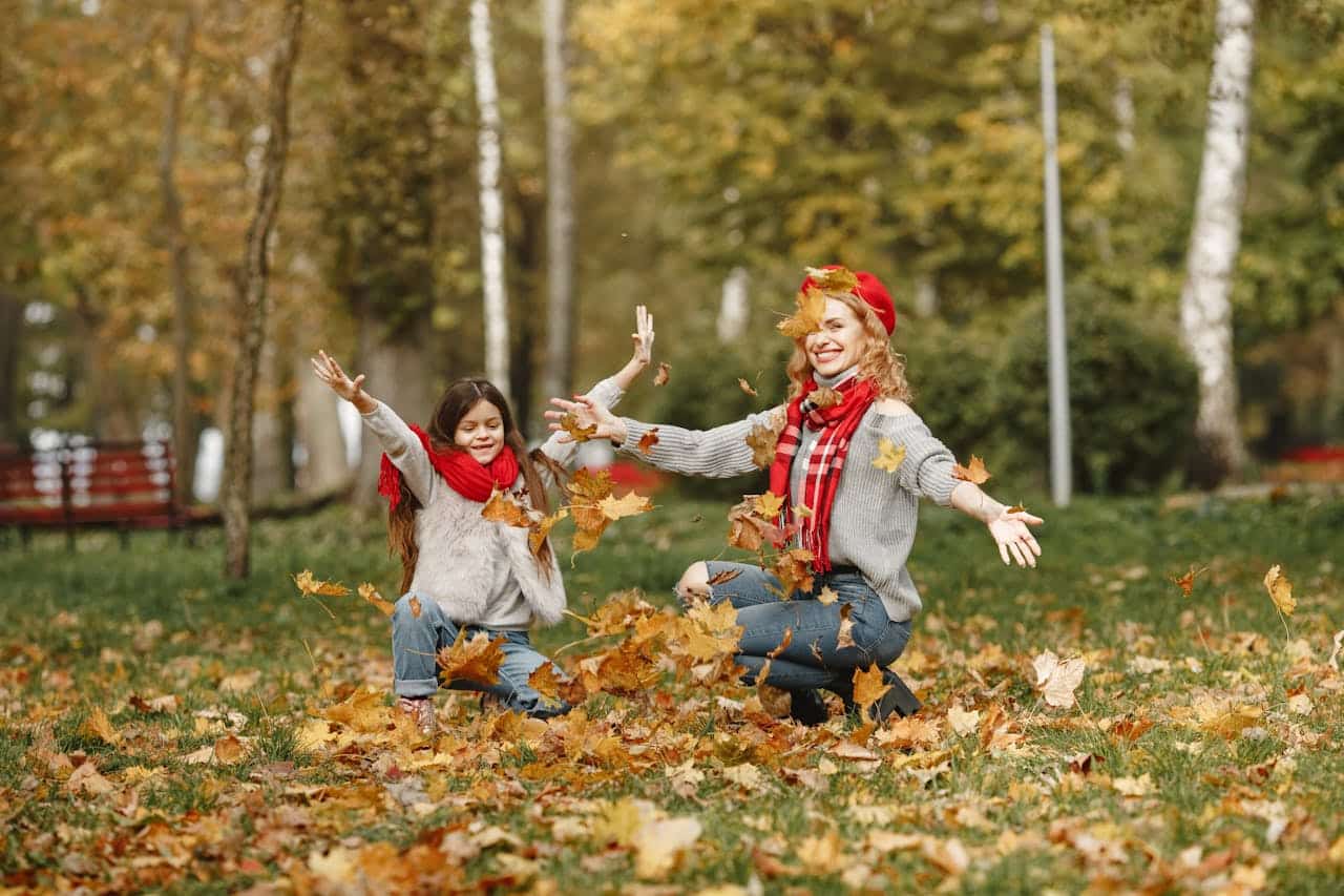 mom and autistic daughter playing with autumn leaves