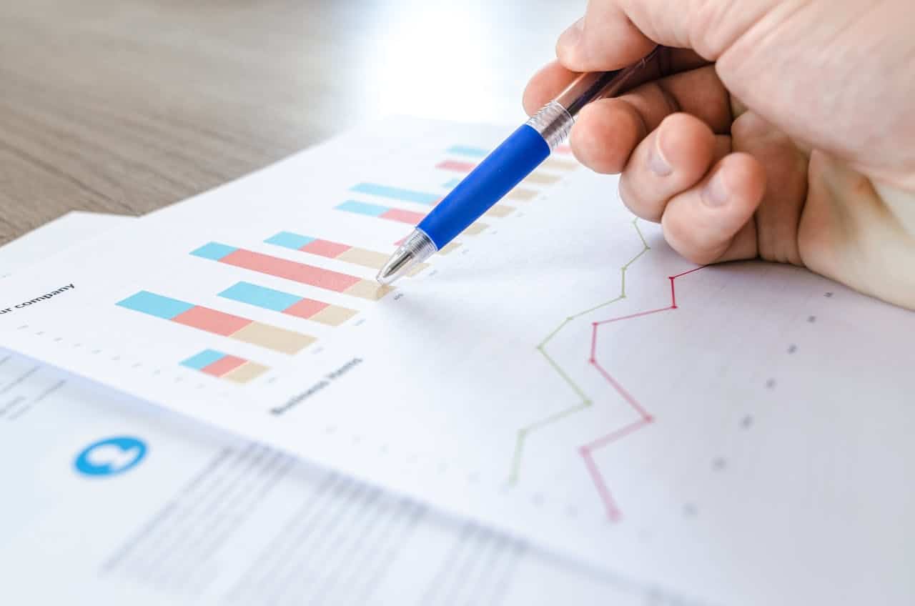 person tapping the graph on paper with a ballpen