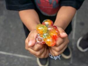 A kid holding and squeezing a colorful stress relief grape balls, autism toys