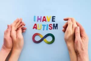 Autistic boy and father hands with rainbow eight infinity symbol. ASD awareness day symbol.