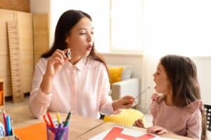 Behavior technician and little girl pronouncing letter O.