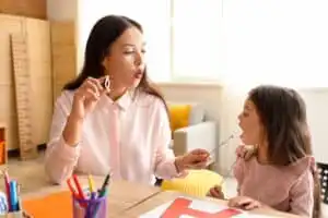 Behavior technician and little girl pronouncing letter O.