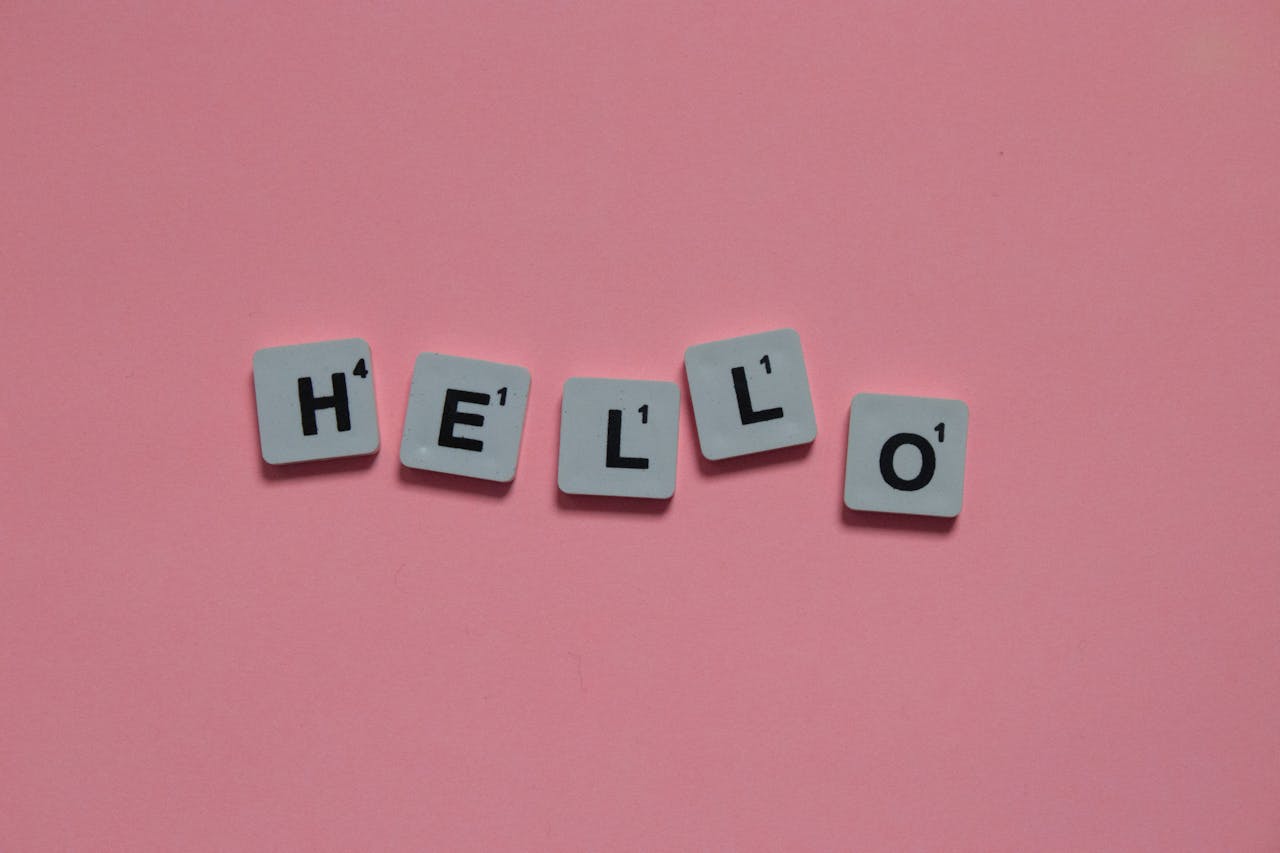 Hello spelled out by scrabble tiles on dark pink backdrop