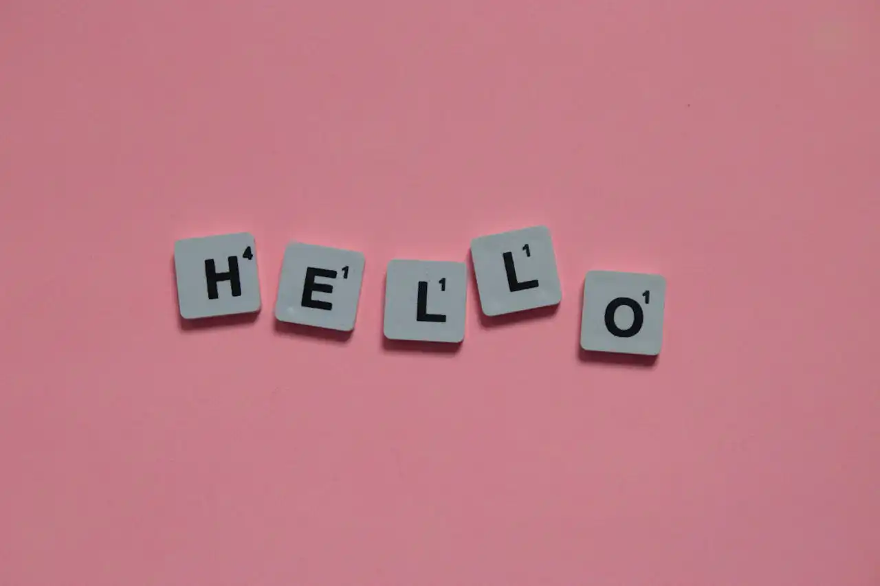 Hello spelled out by scrabble tiles on dark pink backdrop