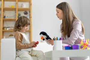 Therapist with her little client playing a penguin doll during ABA Therapy