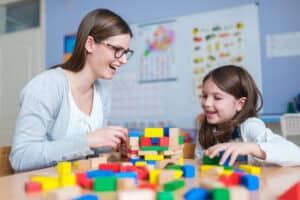 Therapist working with little girl suffering from autistic disorder in office