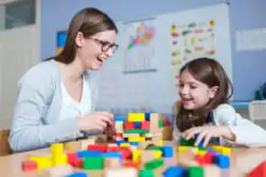 Therapist working with little girl suffering from autistic disorder in office