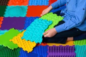 a boy sitting on a sensory mat