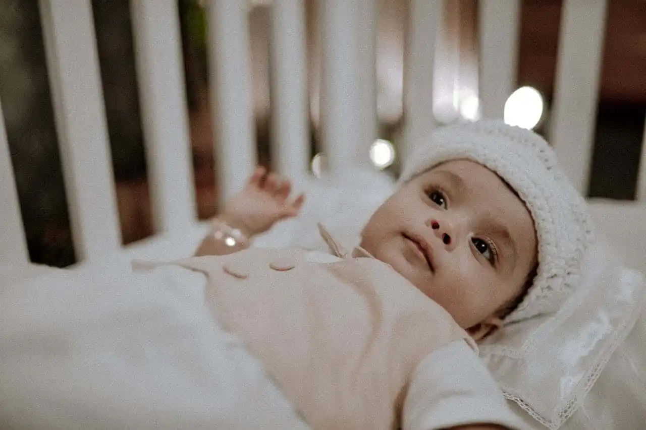 baby laying in crib displaying common autism symptoms in children