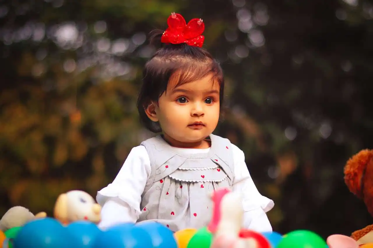 baby girl sitting with a red bow on her hair