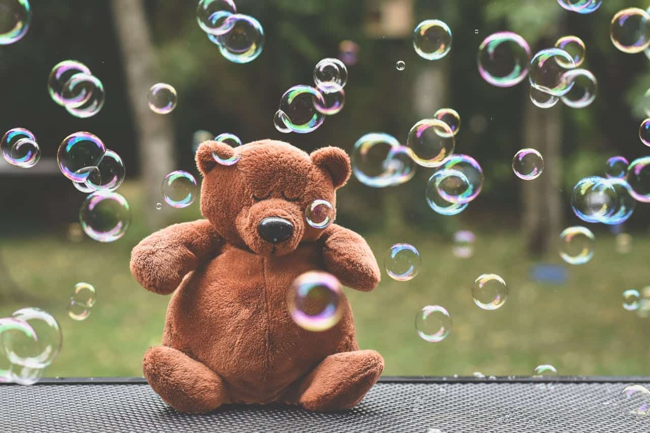 bubbles afloat around a sitting teddy bear