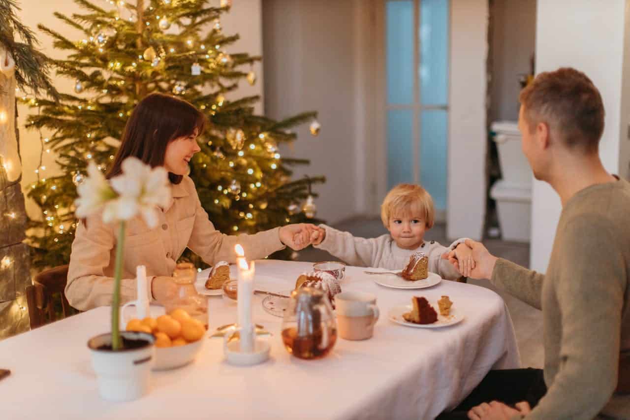 christmas dinner with a family of three holding hands