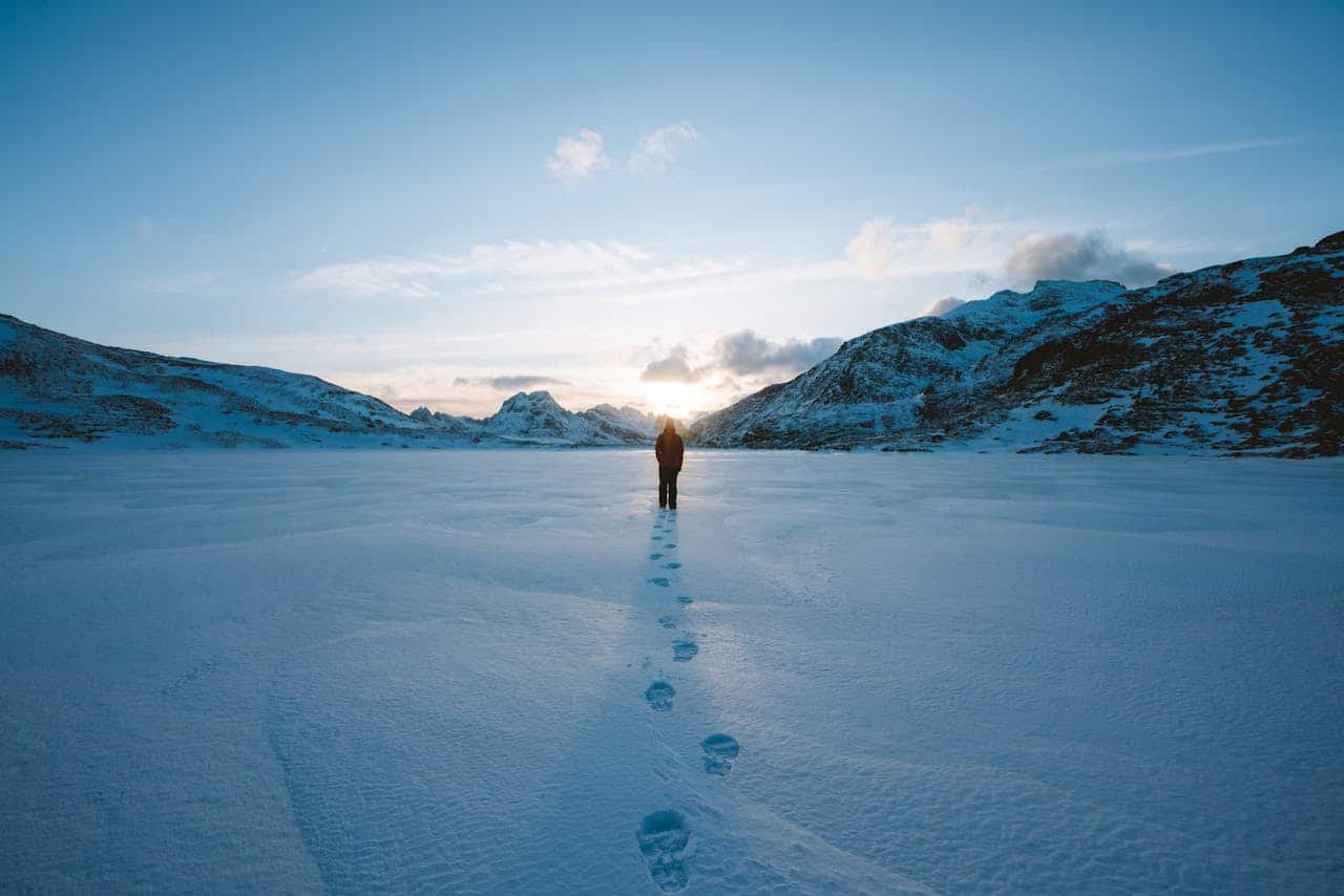 footprints on snow from a man heading toward the mountains