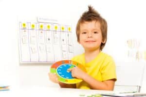 little boy holding a colorful clock for his therapy schedule