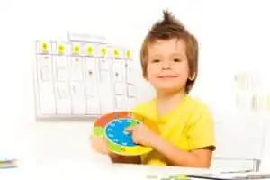 little boy holding a colorful clock for his therapy schedule