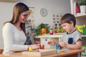 therapist and little boy playing colorful toys for aba therapy