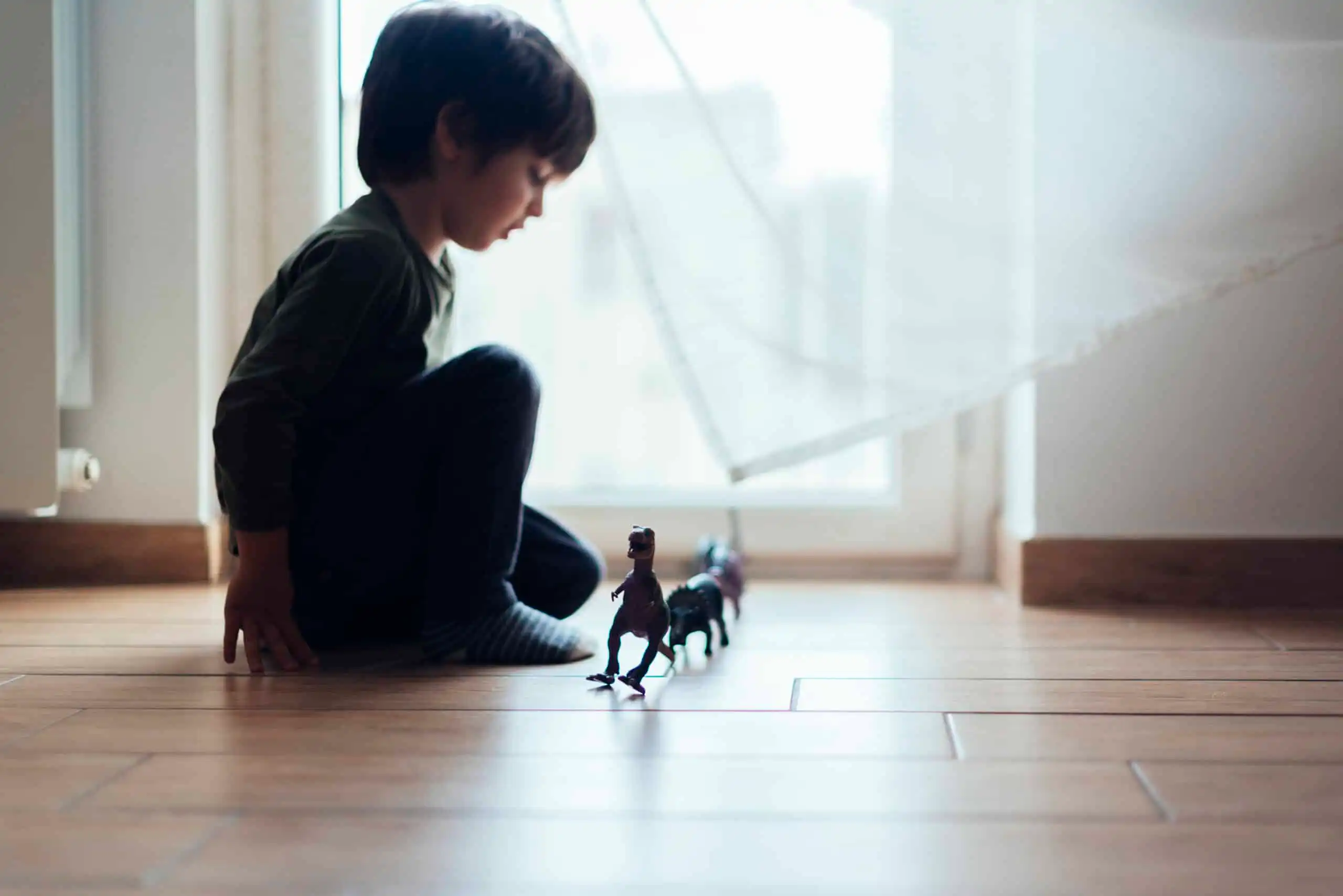 An autistic child playing with his toys in a room alone