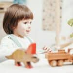 A smiling child with autism playing with wooden toys at a table in a bright room in Maryland.