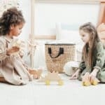 Two autistic girls playing with wooden dinosaur toys during an ABA therapy session in Maryland.