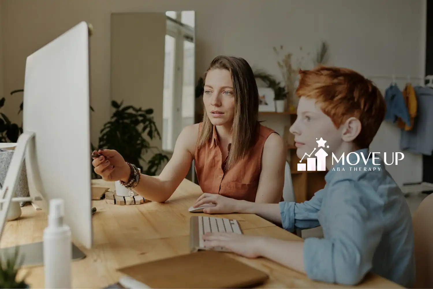 ABA therapist guiding red-haired autistic boy on a desktop computer at a study room in Maryland.