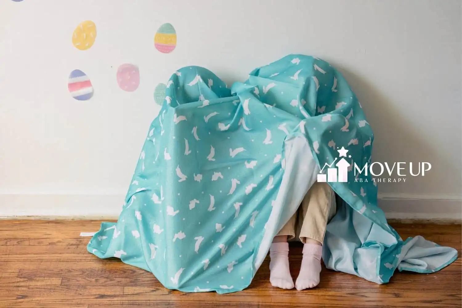 Two kids hiding below a bed sheet