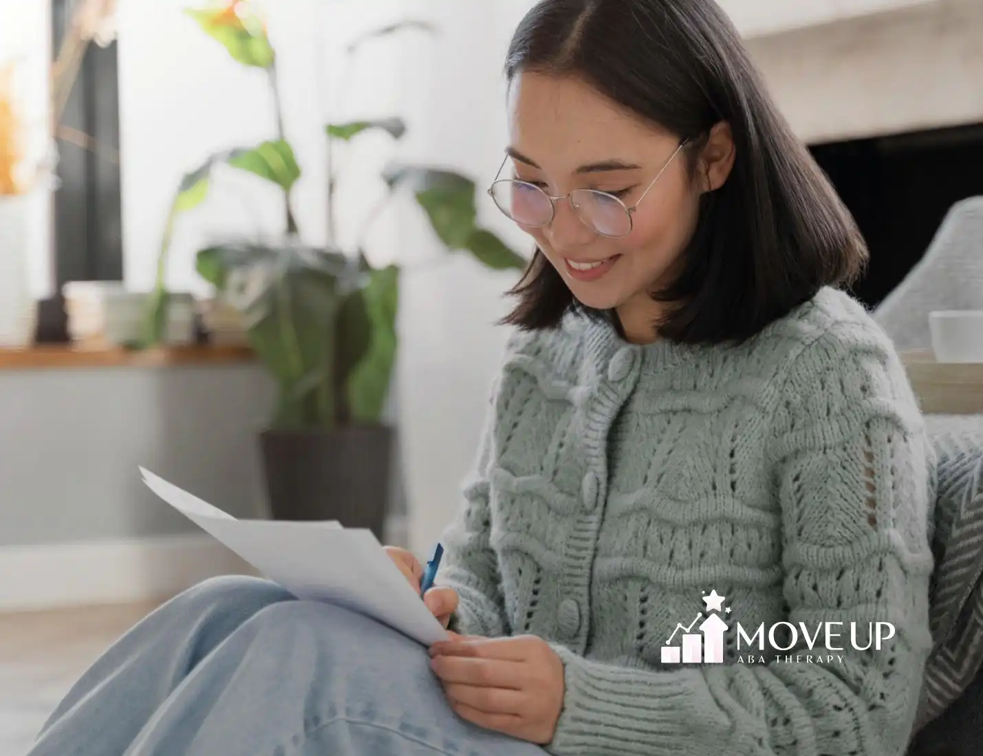 ABA therapist smiling while writing on a piece of paper.