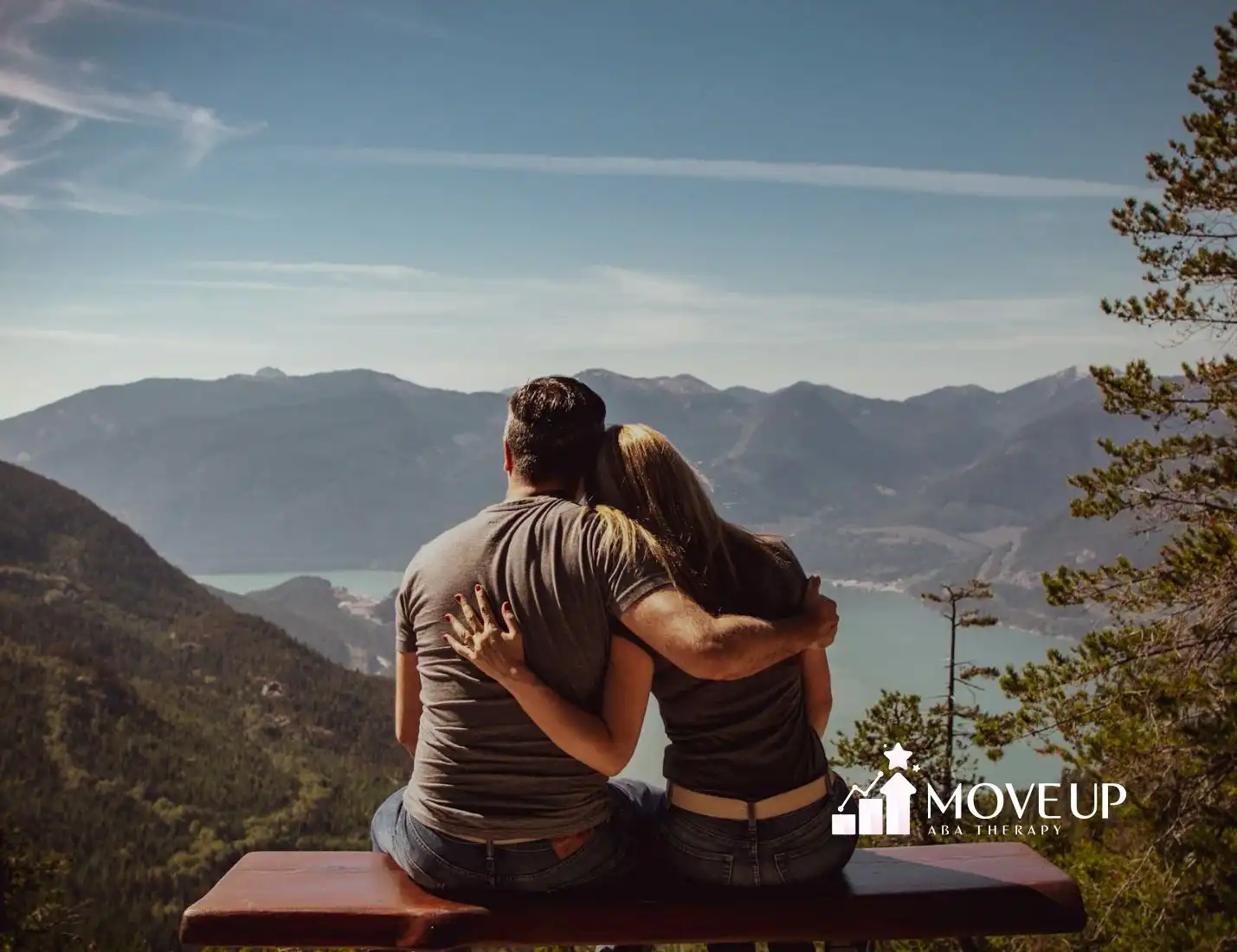 An autistic couple sitting on a bench overlooking a scenic mountain and lake landscape in Maryland.
