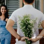 Autistic man hiding flowers behind his back, about to surprise a smiling woman standing nearby in MD.