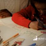 Autistic girl scribbling with markers on a holiday card while ABA therapist watches on her in VA.