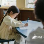 An autistic girl writing on a worksheet at a school desk with stuffed animal in lap in Maryland.