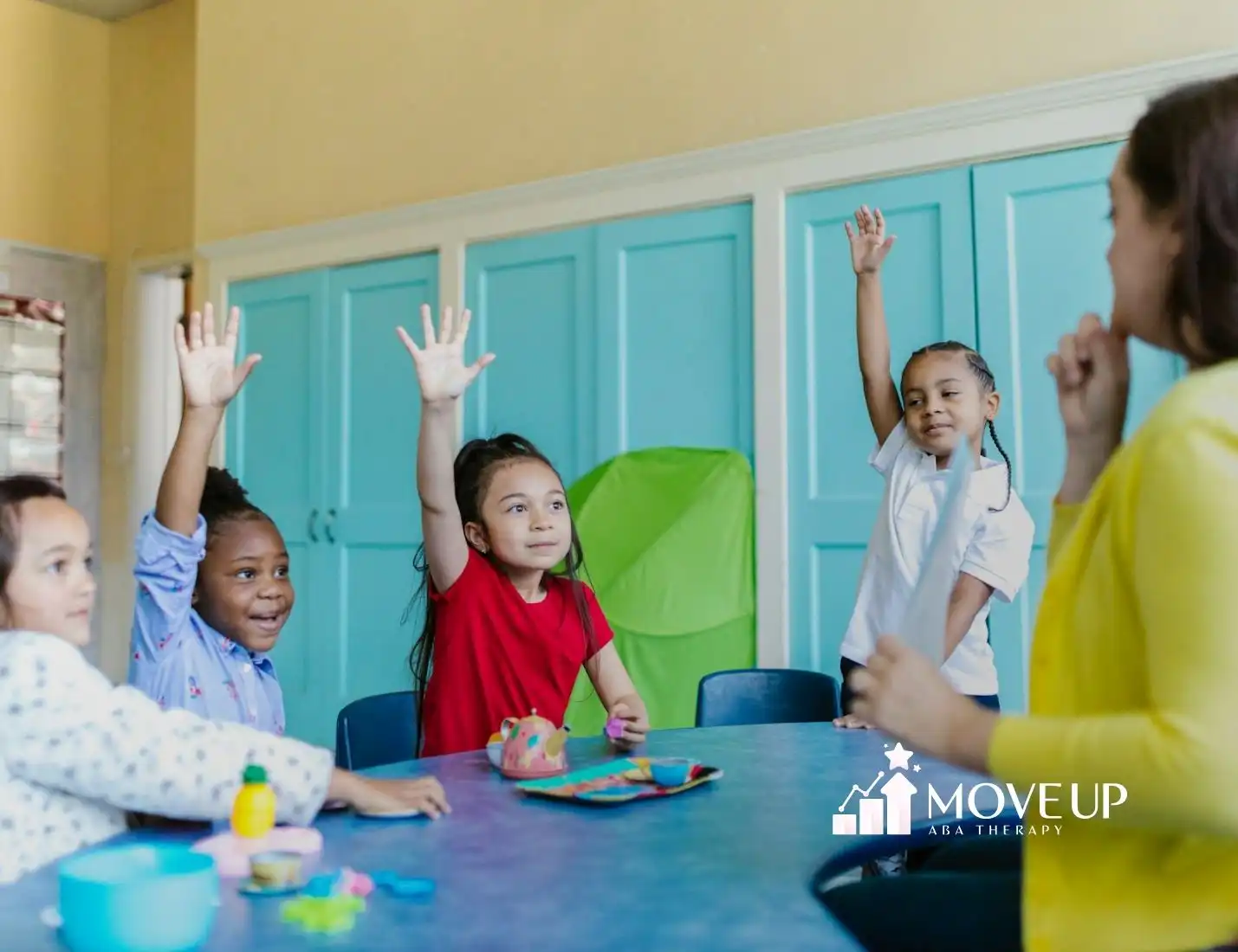 Autistic children raising hands in a classroom during a group activity with a teacher in Virginia.