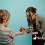 Autistic child receives apple and trophy to a smiling ABA therapist during ABA therapy in Maryland.