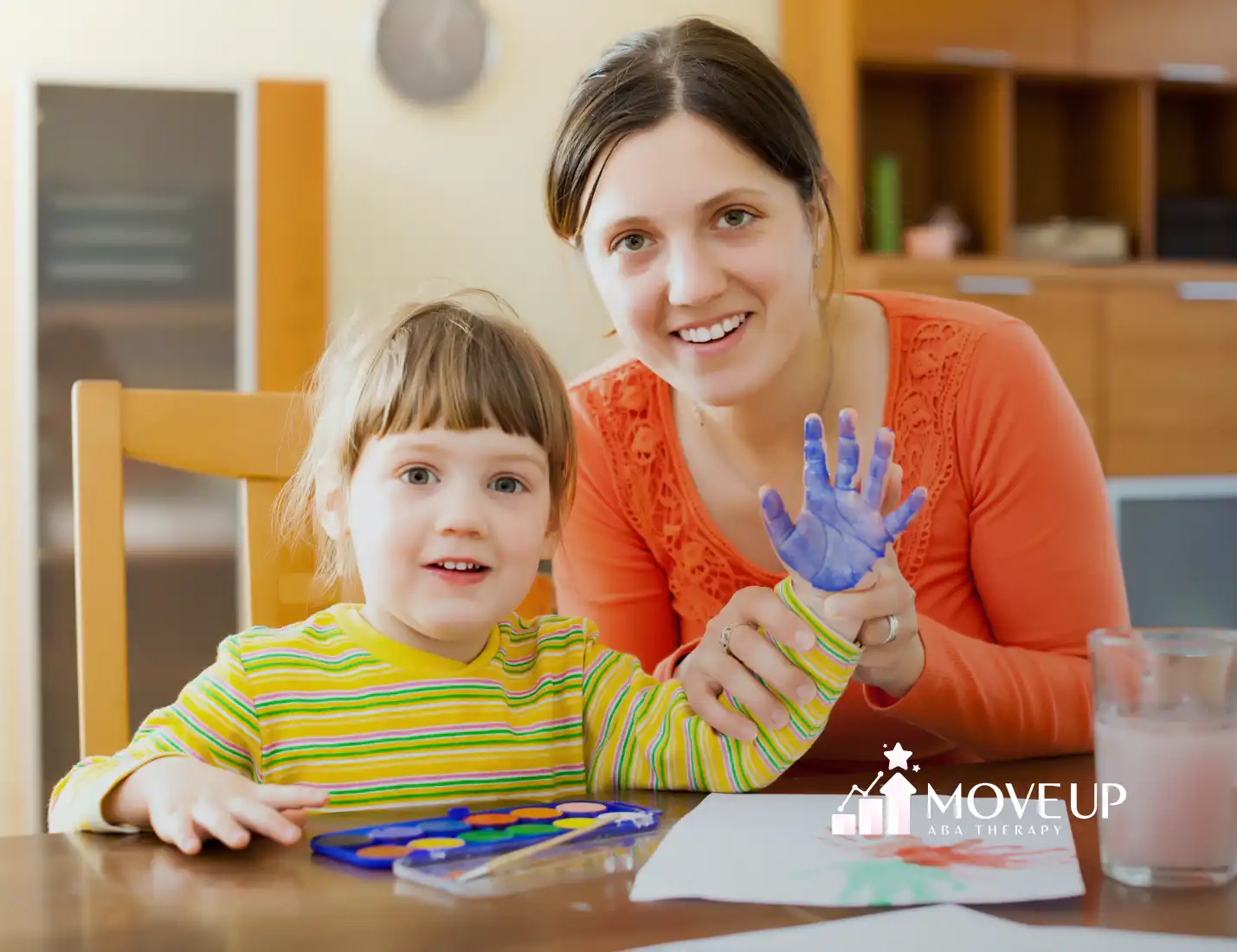 A child with autism and her RBT doing hand painting during ABA therapy
