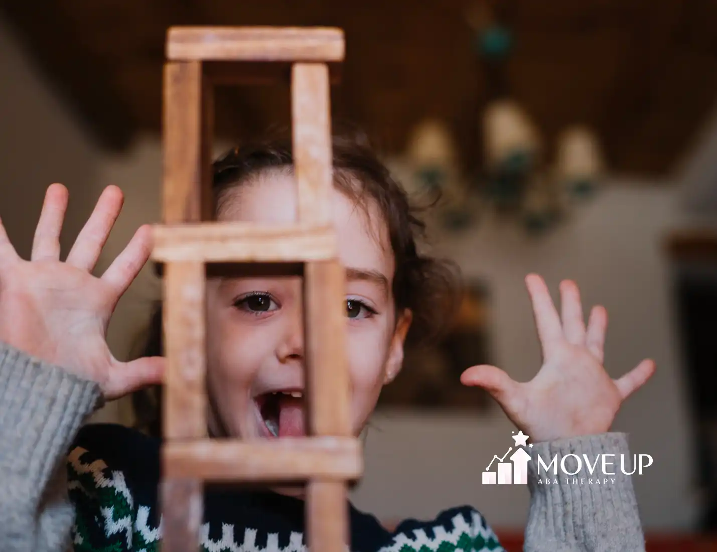 A girl making a silly face behind a small wooden ladder