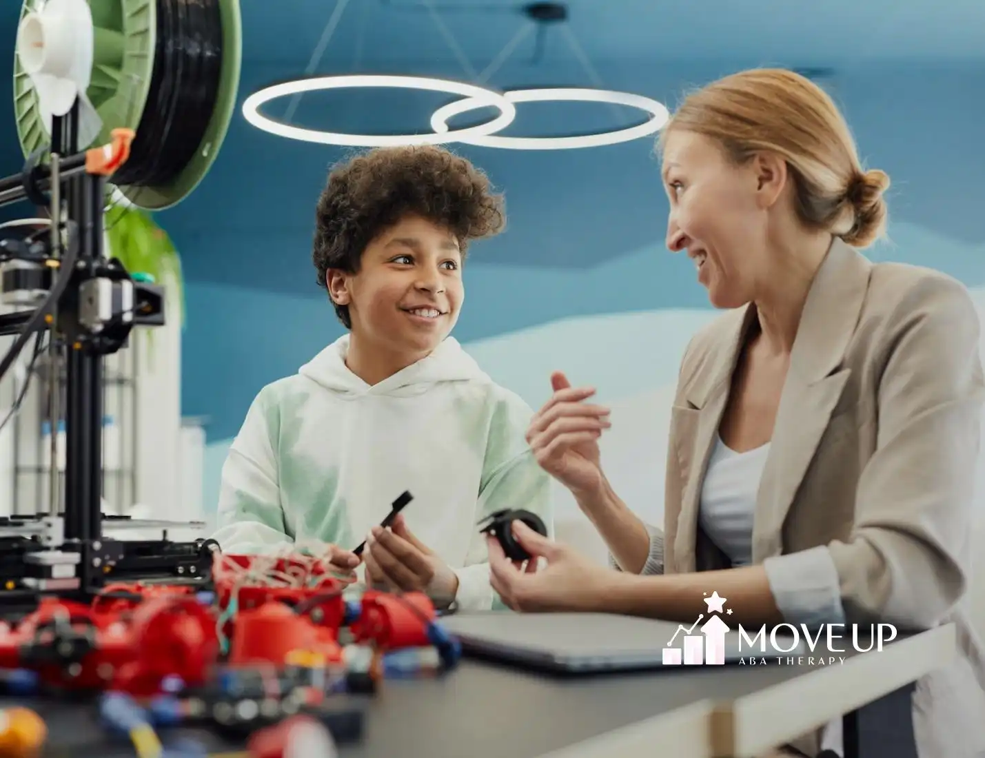 An RBT with her autistic student smiling while working together with robotics in a classroom during ABA therapy in VA.