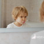 A child is making a face while looking at himself in a mirror