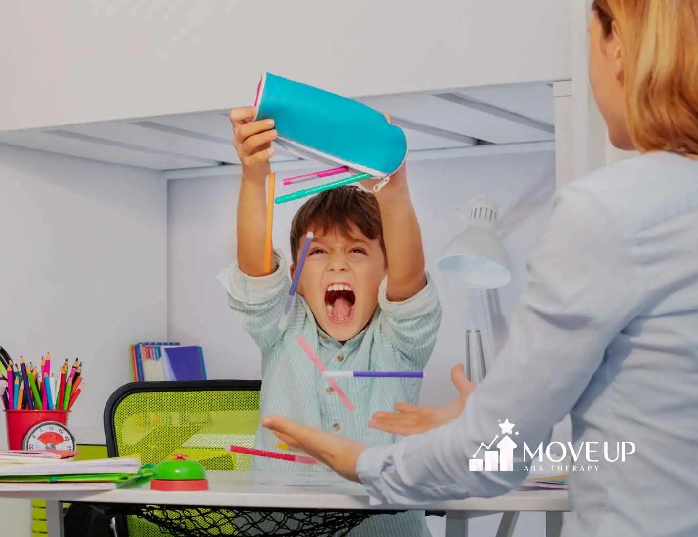 A child excitedly throws pencils from a pencil case, with a playful expression. An adult sits opposite, hands raised. The setting is a colorful study area.