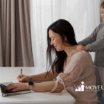 A young boy with autism gives his mother a back massage while she works on a laptop.